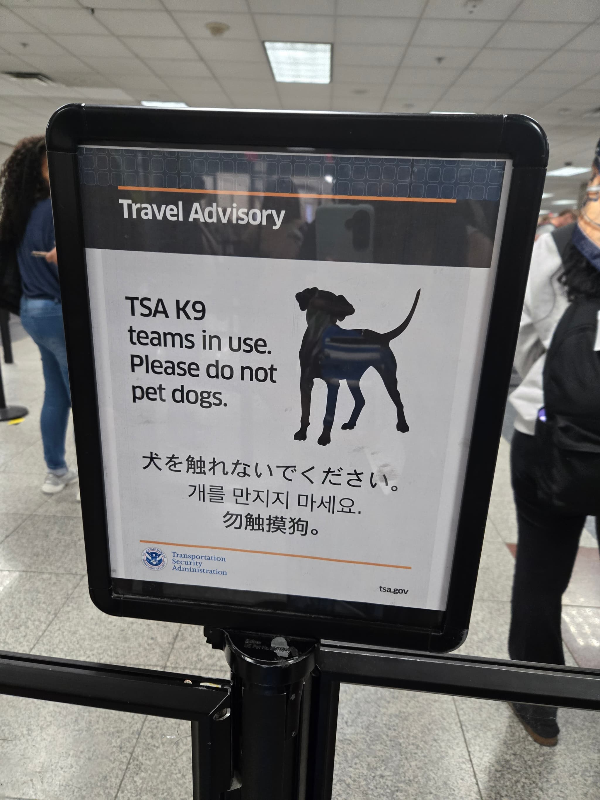 TSA sign saying "Do not pet K9 dogs" in various languages"